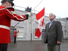 Kingston writer and political historian Arthur Milnes watches Cpl. MacGregor Van De Ven, left, and Pvt. Chris Neely of the Fort Henry Guard on June 29 raise a Canadian flag that once flew over the Peace Tower in Ottawa that Milnes received. The flag is to fly over the fort on Canada Day. (Elliot Ferguson/The Whig-Standard)