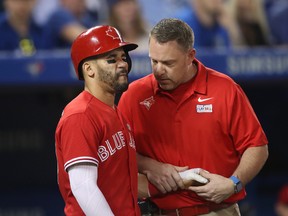 Devon Travis of the Toronto Blue Jays reacts after being hit by a pitch on the hand as trainer Mike Frostad tends to him during MLB action against the New York Yankees at Rogers Centre on June 4, 2017. (Tom Szczerbowski/Getty Images)