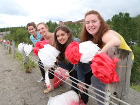 Zoe Monet, left, Kayla Katerynuk, Abbie Glass and Chelsea Katerynuk, of Glad Tidings Church in Sudbury, Ont., put decorations on a guard rail near the church on Regent Street on Friday June 30, 2017, in preparation for Canada Day. The church is hosting Canada Day celebrations, which will include a free barbecue and family activities. John Lappa/Sudbury Star/Postmedia Network
