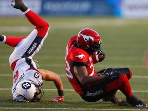 Calgary Stampeders Jerome Messam is knocked to the turf by Antoine Pruneau of the Ottawa Redblacks during CFL football in Calgary. (AL CHAREST/POSTMEDIA Network)