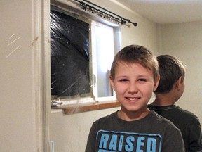 Zach Landis, 11, poses under claw marks and a blood stain left by a bear after it crashed through his bedroom window in Anchorage, Alaska, Friday, June 30, 2017. (AP Photo/Mark Thiessen)