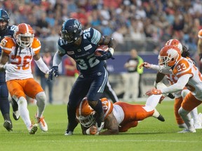 Toronto Argonauts running back James Wilder Jr., centre, is tackled by BC Lions' DeQuin Evans during second half CFL football action in Toronto on Friday, June 30, 2017. (THE CANADIAN PRESS/Chris Young)