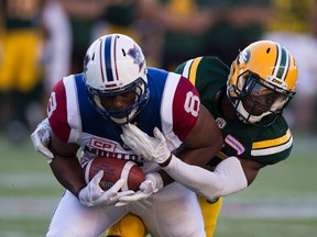 Edmonton Eskimos Kenny Ladler (37) tackles Montreal Alouettes Nik Lewis (8) during first half CFL action on Friday June 30, 2017, in Edmonton.