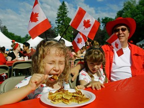 Olivia Jaycox (left/5-years-old) eats pancakes with her twin sister Janeen and dad Dave at the Canada Day pancake breakfast held on the grounds of the Alberta Legislature on Canada Day. The breakfast was put on by the Ismaili Council for Edmonton. (PHOTO BY LARRY WONG/POSTMEDIA)