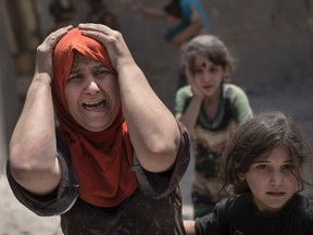A woman screams while fleeing with her family through a destroyed alley, as Iraqi Special Forces continue their advance against Islamic State militants, in the Old City of Mosul, Iraq, Sunday, July 2, 2017. (AP Photo/Felipe Dana)
