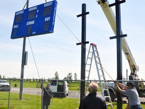 Employees of JF Skinner Builders and volunteers with Mitchell Minor Baseball work together to hoist a new $9,000 electronic scoreboard despite tricky winds last Thursday, June 29 at Cooper Standard baseball field in Kinsmen Park. The scoreboard, built by OES in London, will have the field’s name and Cooper Standard’s logo on top and a large advertising bar courtesy of Airtech added at some point this week. The scoreboard, located in right field (so it doesn’t interfere with the sun), is scheduled to be in use this week. Also planned this summer are new park advertising signs which will be erected around the perimeter of the outfield fence. ANDY BADER/MITCHELL ADVOCATE