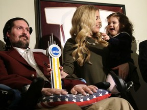 FILE - In this Dec. 13, 2016, file photo, former Boston College baseball captain Pete Frates, left, appears with his wife Julie, center, and two-year-old daughter Lucy, right, moments after he was presented with the 2017 NCAA Inspiration Award, at their home in Beverly, Mass.(AP Photo/Steven Senne, File)