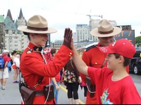 Noam Kaplan-Myrth photographed high-fiving a Mountie in downtown Ottawa on Saturday. Noam's brother art is compiling 150 photos of his brother high-fiving strangers. (Art Kaplay-Myrth)