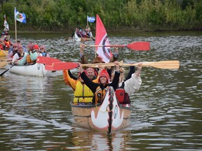 The Athabasca River Brigade raise their paddles in greeting as they prepare to land their canoes at River Boat Park on June 27 (Peter Shokeir | Whitecourt Star).