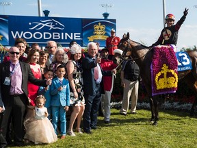 Magna International founder Frank Stronach and Luis Contreras, aboard Holy Helena pose in the winners circle, after the Stronach Stables horse won the 158th running of the Queen's Plate on Sunday. (Mark Blinch/The Canadian Press)