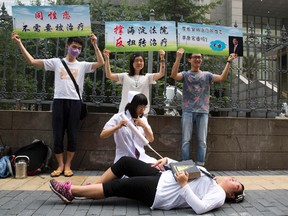 In this July 31, 2014 file photo, gay rights campaigners act out electric shock treatment to protest outside a court when the first court case in China involving so-called conversion therapy is held in Beijing, China. A gay man in central China has successfully sued a mental hospital over forced conversion therapy on June 26, 2017, in what activists are hailing as the first such victory in the country where the LGBT rights movement is gradually emerging form the fringes. (AP Photo/Ng Han Guan, File)
