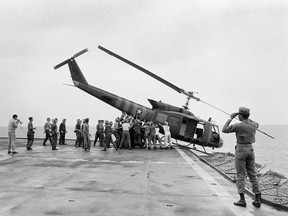 In this Tuesday, April 29, 1975 file photo, U.S. Navy personnel aboard the USS Blue Ridge push a helicopter into the sea off the coast of Vietnam in order to make room for more evacuation flights from Saigon. The helicopter had carried Vietnamese people fleeing Saigon as North Vietnamese forces closed in on the capital. (AP Photo/File)