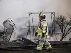 The Grand Blanc Fire Department responds to a garage fire Monday evening, July 3, 2017, with assistance from Burton and Mundy Township on the 6000 block of Grove Avenue in Grand Blanc Township, Mich. The homeowner attempted to use fireworks to remove a bees' nest from the building, fire officials said. (Shannon Millard/The Flint Journal-MLive.com via AP)