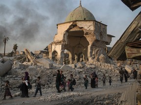 Fleeing Iraqi civilians walk past the heavily damaged al-Nuri mosque as Iraqi forces continue their advance against Islamic State militants in the Old City of Mosul, Iraq, Tuesday, July 4, 2017. As Iraqi forces continued to advance on the last few hundred square kilometers of Mosul held by the Islamic State group, the country's Prime Minister said Tuesday the gains show Iraqis reject terrorism. (AP Photo/Felipe Dana)