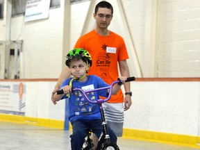 Xander Mosey rides his bike alongside volunteer Alexandre Laflamme at the iCanBike program on Wednesday at Constantine Arena. The program teaches children from the KidsInclusive Centre for Child and Youth Development how to ride a bicycle. (Joseph Cattana/The Whig-Standard)