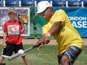 Andre Thompson, 11, pounds out a hit in front of catcher Todd Joseph, 5, on training day Wednesday for the 24th annual Rookie League at Labatt Park. (MORRIS LAMONT, The London Free Press)