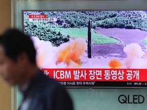 A man walks by a TV screen showing a local news program reporting about North Korea's missile firing at Seoul Train Station in Seoul, South Korea, Wednesday, July 5, 2017. North Korea's leader Kim Jong Un vowed his nation would "demonstrate its mettle to the U.S." and never put its weapons programs up for negotiations a day after test-launching its first intercontinental ballistic missile. The hard line suggests more tests are being prepared as the country tries to perfect a nuclear missile capable of striking anywhere in the United States. The letters read "North Korea, release an ICBM launching video." (AP Photo/Lee Jin-man)