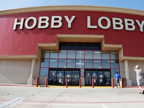 In this June 30, 2014, file photo, customers walk to a Hobby Lobby store in Oklahoma City. Federal prosecutors say Hobby Lobby Stores has agreed to pay a $3 million federal fine and forfeit thousands of ancient Iraqi artifacts smuggled from the Middle East that the government alleges were intentionally mislabled. Prosecutors filed a civil complaint in New York on Wednesday, July 5, 2017, in which Oklahoma City-based Hobby Lobby consented to the fine and forfeiture of thousands of tablets and bricks written in cuneiform, one of the earliest systems of writing, as well as other artifacts that prosecutors say were shipped without proper documentation. (AP Photo/Sue Ogrocki, File)