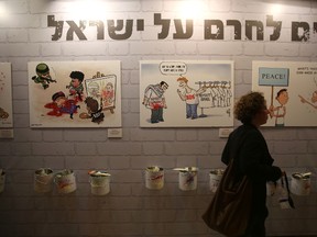 A woman walks past caricatures of Israeli artists against the Palestinian-led Boycott, Divestment and Sanctions (BDS) movement displayed during the Ynet and Yedioth Ahronoth's anti-BDS conference on March 28, 2016, in Jerusalem. MENAHEM KAHANA/AFP/Getty Images