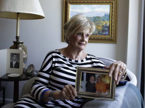 Rita Bisson's late husband François was a resident at the Garry J. Armstrong long-term care facility. She sat for a portrait, holding a cherished photograph, with paintings by François hanging on the wall in her apartment on July 5, 2017. (DAVID KAWAI / POSTMEDIA)