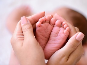 A woman cradles a newborn baby's feet in this stock photo. (Getty Images)
