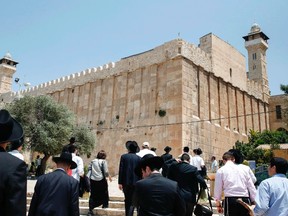 A picture taken on July 7, 2017 shows religious Jews and tourists walking towards the Cave of the Patriarchs, also known as the Ibrahimi Mosque, which is a holy shrine for Jews and Muslims, from the Israeli side in the heart of the divided city of Hebron in the southern West Bank. On July 7, 2017 UNESCO declared in a secret ballot the Old City of Hebron in the occupied West Bank a protected heritage site. HAZEM BADER/AFP/Getty Images