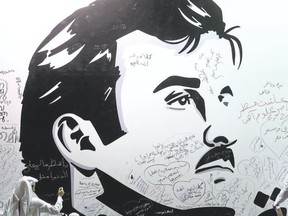 Qataris write comments on a wall bearing a portrait of Qatar?s emir, Sheikh Tamim bin Hamad Al Thani, who has become the symbol of Qatari resistance during the month-long row with neighbouring countries. (KARIM JAAFARKARIM JAAFAR/AFP)