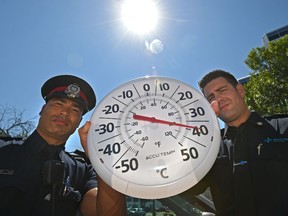 EPS Sgt. Lael Sauter (L) with Child at Risk Response Team (CARRT) and Alex Campbell, Paramedic and Public Information Officer with EMS holding a thermometer that was reading 50º C plus after less then five minutes of sitting in a vehicle in Edmonton, July 7, 2017. Ed Kaiser/Postmedia