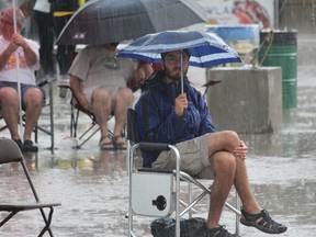 Johnny Mills attempts to brave the rain during Friday night's Sunfest downpour at Victoria Park. (CHARLIE PINKERTON/London Free Press/Postmedia Network)