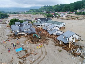 Firefighters inspect the collapsed houses in the mud following the flooding caused by heavy rain in Asakura, Fukuoka prefecture, southwestern Japan, Saturday, July 8, 2017. (Koji Harada/Kyodo News via AP)