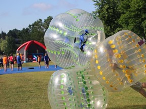 Josh Gateman of Bill Gosling Outsourcing topples a tower of inflatable bubbles at Corporate Challenge 2017 at Harris Park. (CHARLIE PINKERTON/London Free Press/Postmedia Network)