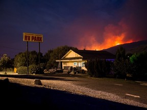 A wildfire burns on a mountain behind an RV park office in Cache Creek, B.C., in the early morning hours of Saturday July 8, 2017. More than 3,000 residents have been evacuated from their homes in central British Columbia. A provincial state of emergency was declared after 56 new wildfires started Friday. THE CANADIAN PRESS/Darryl Dyck