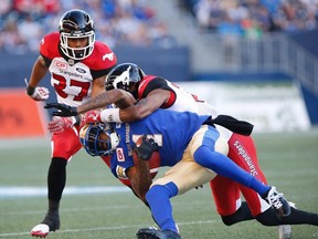 Winnipeg Blue Bombers' Darvin Adams (1) gets tackled by Calgary Stampeders' Tommie Campbell (25) during the first half of CFL action in Winnipeg Friday, July 7, 2017. THE CANADIAN PRESS/John Woods