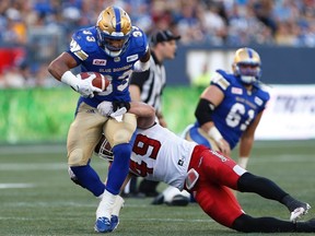 Winnipeg Blue Bombers' Andrew Harris (33) breaks the tackle by Calgary Stampeders' Alex Singleton (49) during the first half of CFL action in Winnipeg Friday, July 7, 2017. THE CANADIAN PRESS/John Woods