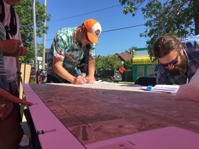 Shawn Lucaschuk (left) goes over plans for the eastern corridor expansion of rapid transit to the northeast corner Winnipeg at a pop-up event held by the City of Winnipeg at the Kildonan Mennonite Central Committee Farmers Market in Elmwood on Saturday, July 8, 2017. The event was held to get public feedback on what residents would like to see out of the eastern corridor and where they would like it to go.  
JASON FRIESEN/Winnipeg Sun/Postmedia Network
