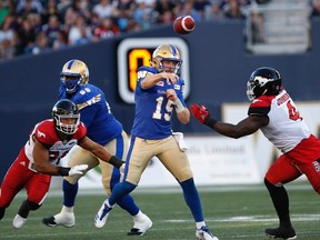 Winnipeg Blue Bombers quarterback Matt Nichols (15) gets the ball away despite pressure from Calgary Stampeders' Micah Johnson (4) and James Vaughters (98) during the first half of CFL action in Winnipeg Friday, July 7, 2017. THE CANADIAN PRESS/John Woods