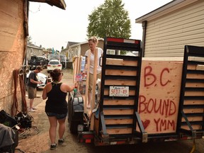 Crystal Purcell, 32, gives a handful of gift cards to Tamara Laverdiere, 35, as they load a trailer with donated supplies intended for fire halls and evacuation centres in B.C., where wildfires are spreading quickly. The trailer will hold supplies ranging from water and Gatorade to eye drops and sunscreen, in Fort McMurray, Alta. on Saturday, July 8, 2017. Cullen Bird/Fort McMurray Today/Postmedia Network.