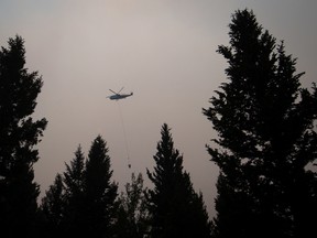 A helicopter carrying a bucket battles the Gustafsen wildfire near 100 Mile House, B.C., on Saturday July 8, 2017. More than 180 fires were burning, many considered out of control, as the B.C. government declared a provincewide state of emergency to co-ordinate the crisis response. Officials said buildings have been destroyed, but they did not release numbers. The BC Wildfire Service says over 173 fires were reported on Friday alone as lightning storms rolled over several parts of B.C. (THE CANADIAN PRESS/Darryl Dyck)