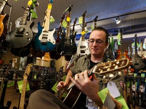 Scott McCarthy, an Axe Music guitar sales representative, plays a Seagull guitar in the company's 11931 Wayne Gretzky Drive location in Edmonton on Saturday, July 8, 2017. Ian Kucerak / Postmedia