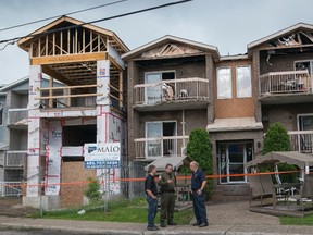 Quebec Provincial Police and Terrebonne police speak with each other after an early morning fatal fire at the Oasis seniors' residence, in Terrebonne, Que., northeast of Montreal, on Sunday, July 9, 2017. Quebec provincial police say a 94-year-old woman has died after an overnight fire tore through a seniors' residence northeast of Montreal. The woman was hospitalized in serious condition following the blaze, which police believe could be criminal in nature. THE CANADIAN PRESS/Peter McCabe