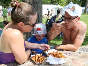 Melanne, Nathaniel and John Gionette dig into their snack of fries and poutine at the London Sunfest on Sunday. (MIKE HENSEN, The London Free Press)