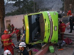 Handout picture released by Andina of firefighters surrounding a tourist bus after it went out of the track in Lima on July 10, 2017. (AFP PHOTO / ANDINA)