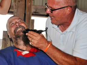 Doug Snyders (right) put the finishing touches on shaving the head and beard of Brad Rapien this past Sunday, July 8, the capper of a “phenomenal” fundraiser Raise it for Rapien. Brad’s 21-year-old son Eli is in London hospital diagnosed in mid-June with a rare form of leukemia, and in just three weeks the community threw together the fundraiser to benefit the Rapien family. Brad’s dad Neil was the winning bidder of $5,000 to shave the hair and beard, with Snyders offering up an additional $500 to finish it. ANDY BADER/MITCHELL ADVOCATE