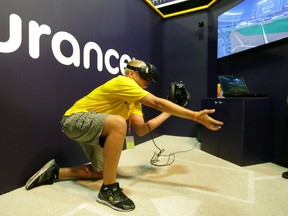 In this Friday, July 7, 2017, photo, Dennis Milman reaches to catch a virtual ball at the All-Star FanFest in Miami Beach, Fla. (AP Photo/Alan Diaz)