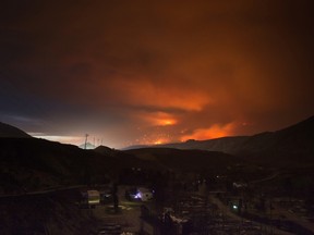 A wildfire burns on a mountain in the distance east of Cache Creek behind a trailer park that was almost completely destroyed by wildfire, in Boston Flats, B.C., in the early morning hours of Monday July 10, 2017. THE CANADIAN PRESS/Darryl Dyck