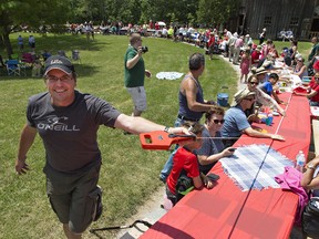 Peter Penner (left) of CJDL Consulting Engineers in Tilsonburg runs a measuring tape along connected picnic table on Saturday at Backus Heritage Conservation Area near Port Rowan.  A new world record was set during Picnic Day in Norfolk County for the longest picnic table with a length of 1,061.94 feet, beating a previous record in France by three feet. Brian Thompson/Postmedia Network