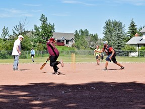 Mike Barkwith (left) oversees the safe line at the pitchers mound. Harley Davidson (middle) stretches his bat in front of him for a soon to be photo finish run, while Sherman Eugene throws the ball at the wicket in an attempt to oust his opponent.