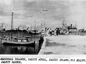 This undated photo discovered in the U.S. National Archives by Les Kinney shows people on a dock in Jaluit Atoll, Marshall Islands. A History Channel documentary proposes that this image shows aviator Amelia Earhart, seated third from right, gazing at what may be her crippled aircraft loaded on a barge. (Office of Naval Intelligence/U.S. National Archives via AP)