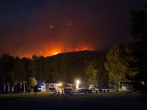 A wildfire burns on a mountain behind a home in Cache Creek, B.C., in the early morning hours of Saturday July 8, 2017. More than 3,000 residents have been evacuated from their homes in central British Columbia. A provincial state of emergency was declared after 56 new wildfires started Friday. THE CANADIAN PRESS/Darryl Dyck