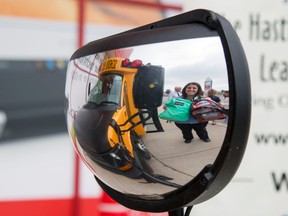 Taylor Bertelink/The Intelligencer
Cindy Martindale holds backpacks up to the mirror of the school bus at the morning kick-off of the Stuff the Bus Campaign. The program provides backpacks filled with school supplies free of charge to local families and students who are in financial need.